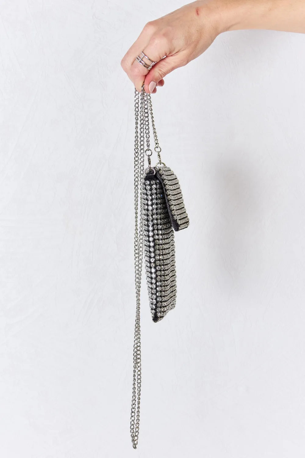 Side view of Chaos Spark Mini Rhinestone Crossbody Bag with silver chain strap held in hand